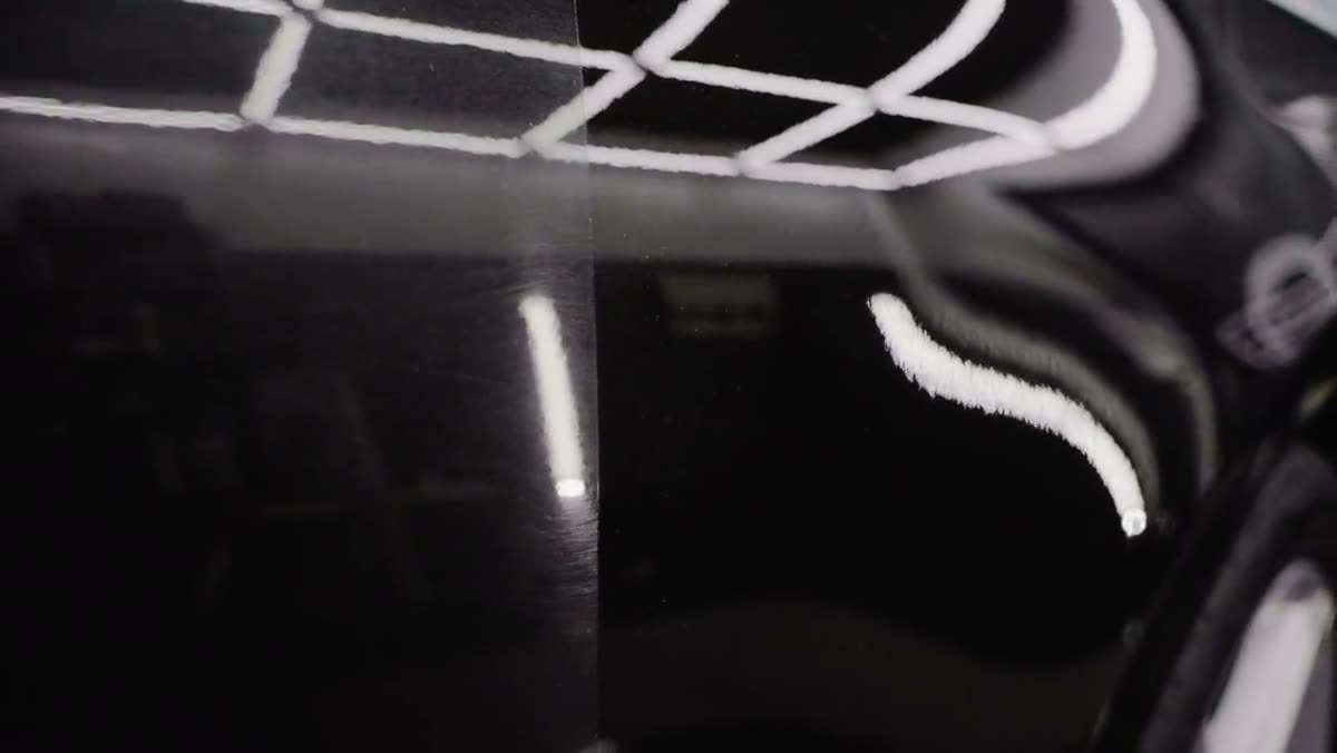 Studio light bars reflecting across black paint during inspection