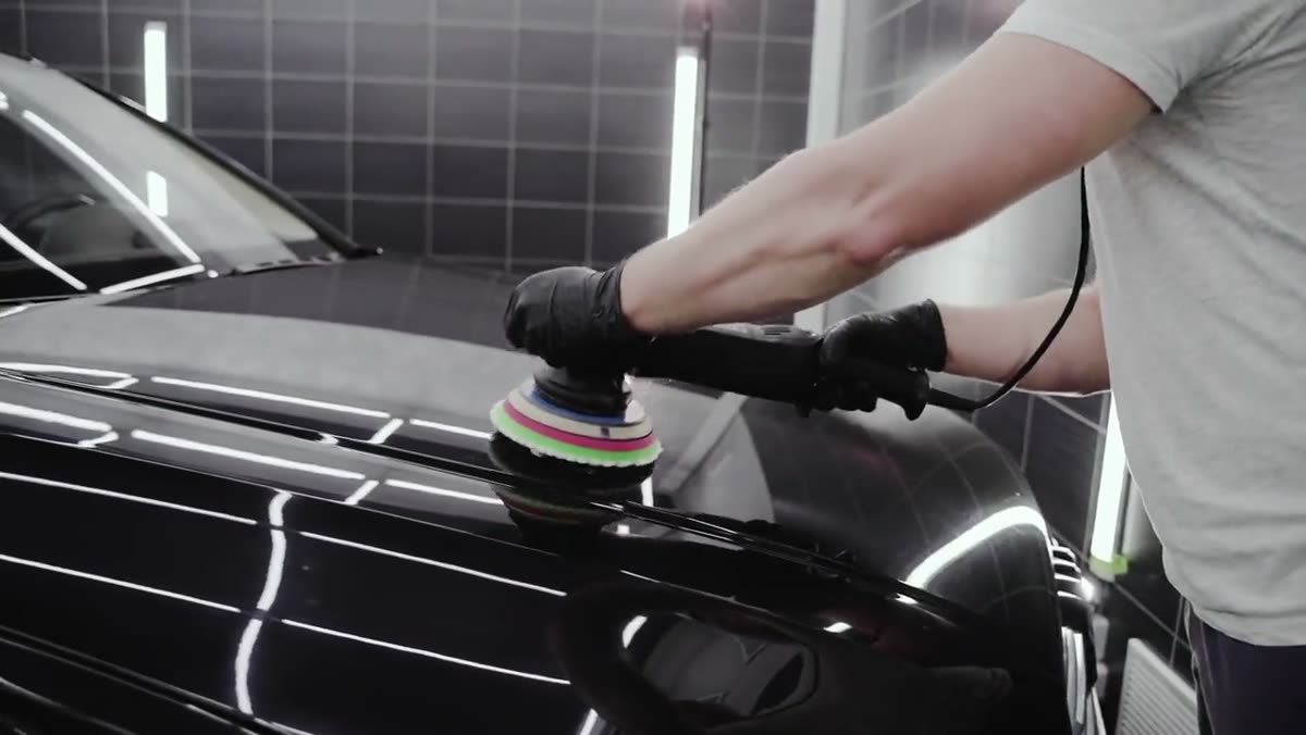 Machine polisher correcting the paint on a black car